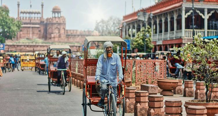 Street scene with rickshaws and Red Fort in the background.