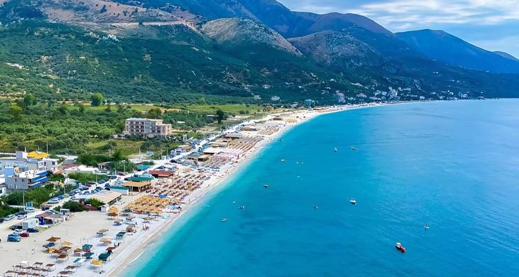 Vue aérienne d'une ville côtière avec une longue plage et une mer bleue.