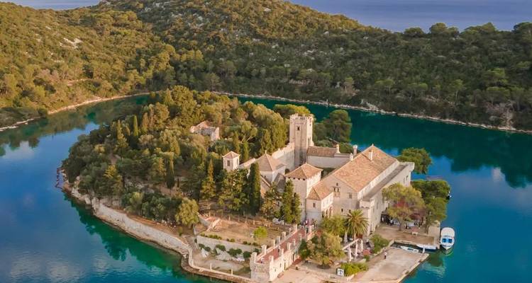 Vue aérienne d'une île avec un bâtiment historique entouré de verdure.