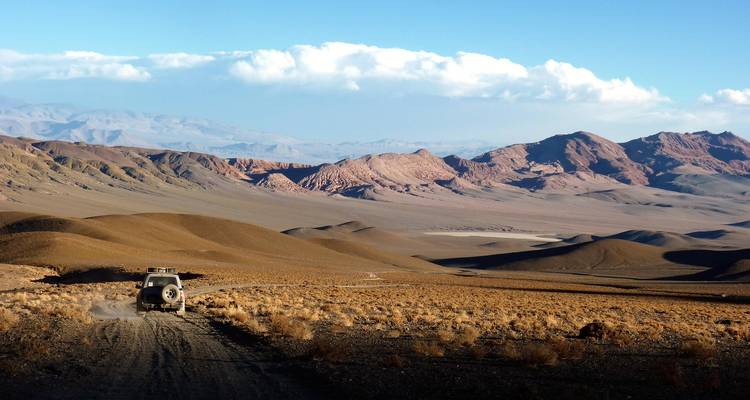 Geländefahrzeug fährt durch eine Wüstenlandschaft.