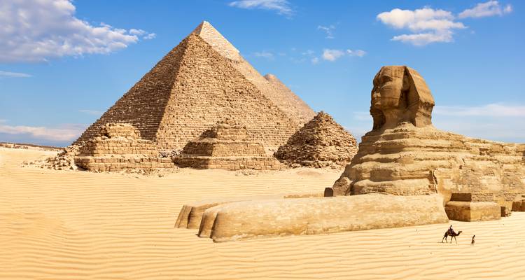 La Gran Pirámide y la Esfinge dominan un paisaje desértico iluminado por el sol con dunas de arena onduladas.