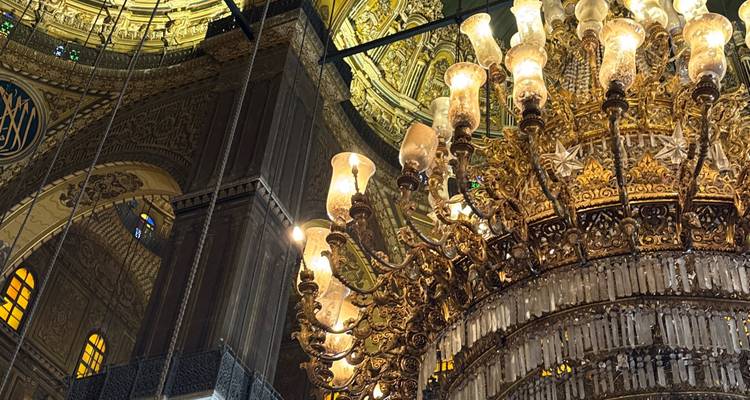 Intérieur complexe avec un grand lustre orné et des détails architecturaux.