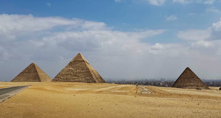 Vue panoramique des pyramides de Gizeh sous un ciel nuageux.