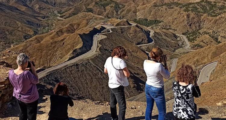 Group of people taking photos of winding roads in mountains.