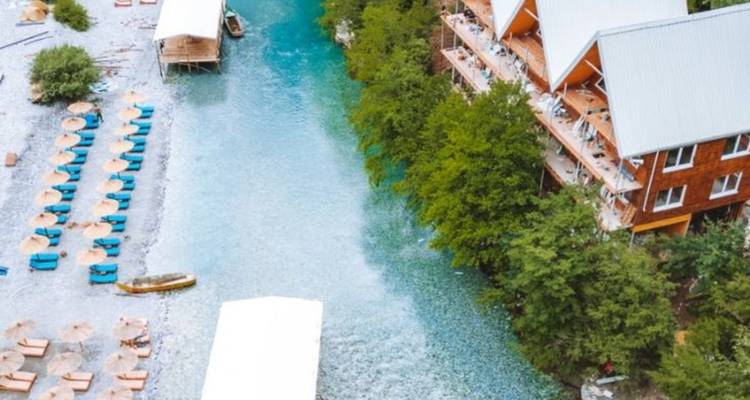 Vue aérienne d'une rivière entourée de verdure et de lodges.