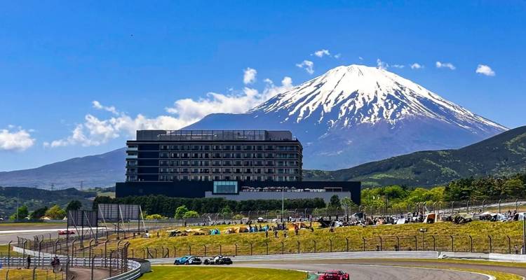 Mount Fuji op de achtergrond met een modern gebouw en een racecircuit.