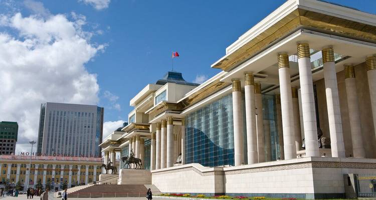 Un bâtiment moderne avec des colonnes et une façade en verre dans un environnement urbain.