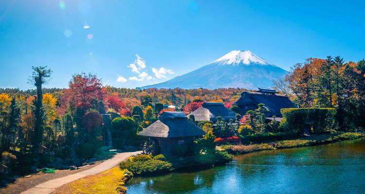 Mount Fuji with colorful autumn trees and a lake in the foreground.