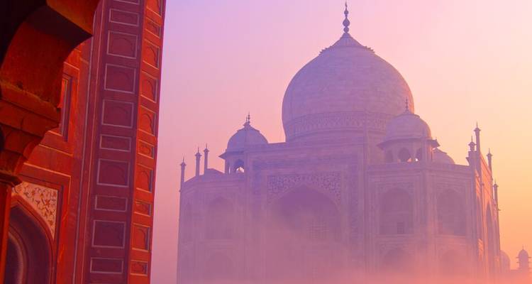 Le Taj Mahal partiellement obscurci par la brume sous un ciel coloré.