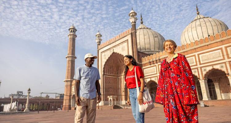 Trois personnes parlant devant une vieille mosquée.