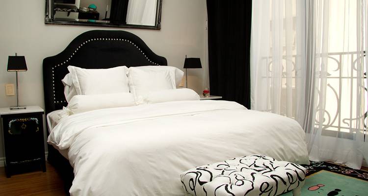 Modern bedroom with white decor and a city view.