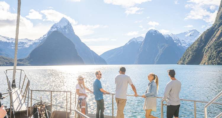 Grupo de personas en un viaje en barco en Milford Sound con vistas montañosas.