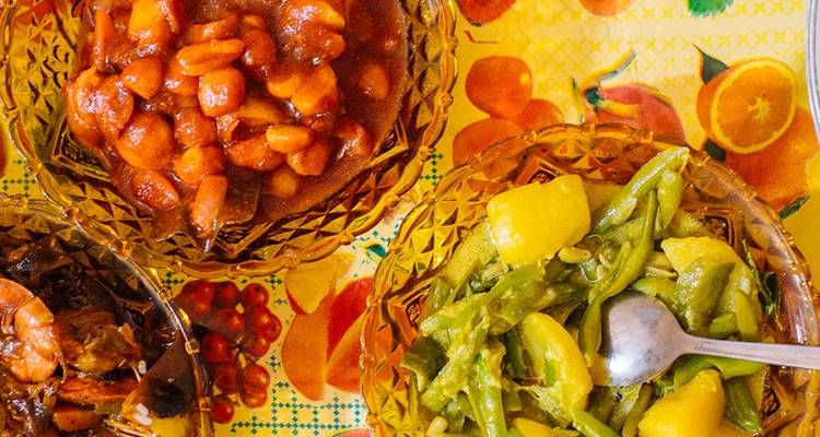 Variété de légumes cuits et de légumineuses dans des bols sur une nappe décorative.