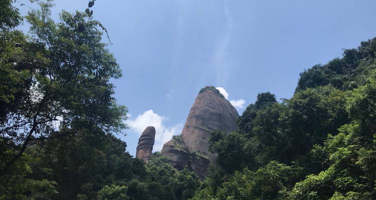 Hoge rotsformaties omgeven door groen onder een heldere blauwe lucht.