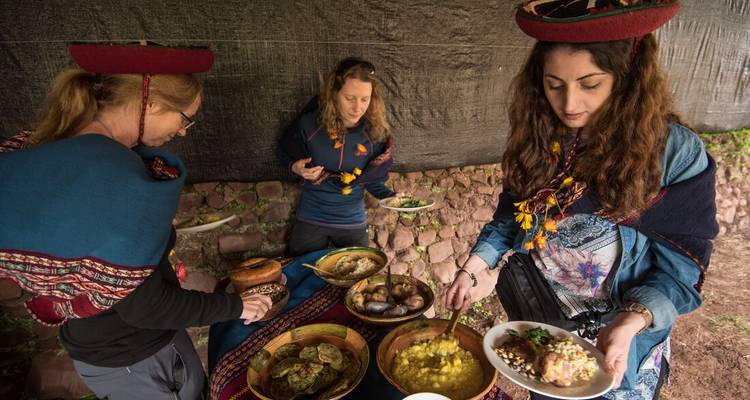People dressed in traditional clothing enjoying a meal with diverse dishes.