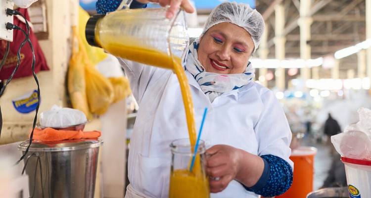 Femme versant un jus frais à un étal de marché.
