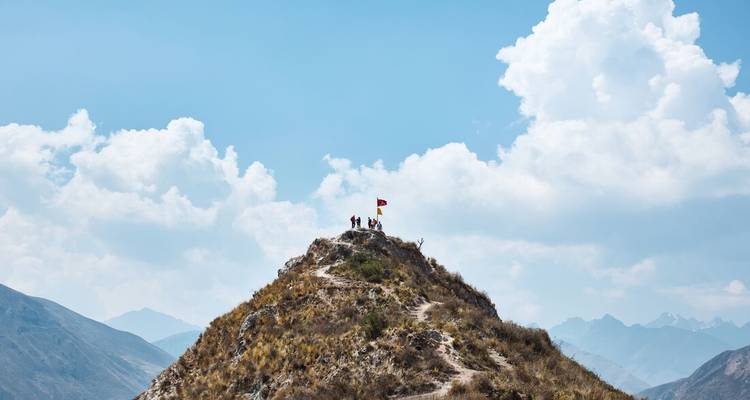 Des gens debout sur un sommet de montagne sous un drapeau.