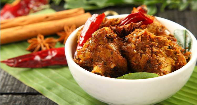 Close-up van Indiase curry in een kom met kruiden ernaast.
