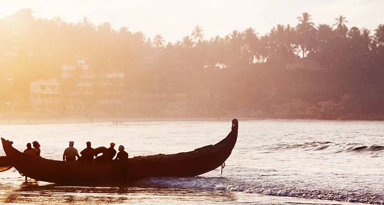 Gesilhouetteerde vissers op een traditionele boot bij zonsopgang.