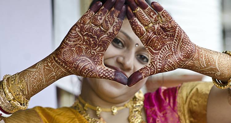 Een vrouw in traditionele kledij die ingewikkelde henna op haar handen toont.