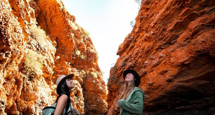 Two women looking up at towering red canyon walls.