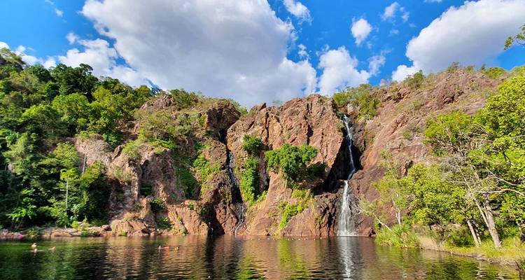 Serene waterfall cascading down rocky cliffs into a calm pool.