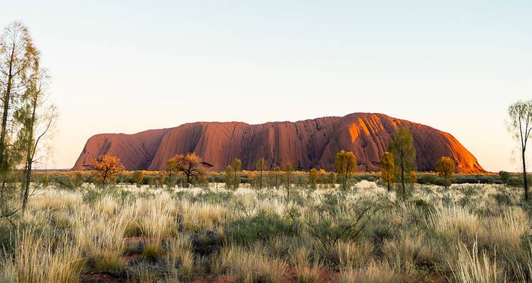 Uluru rock formation during the day with surrounding landscape.
