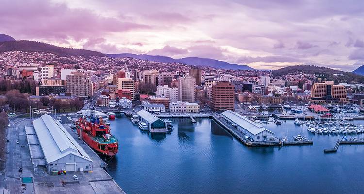 Harbor with boats and buildings at sunset, cityscape in the background.