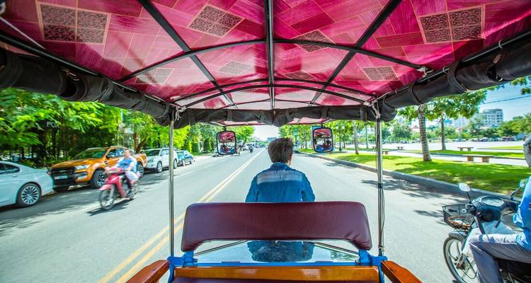 Vue de l'intérieur d'un tuk-tuk dans une rue animée.