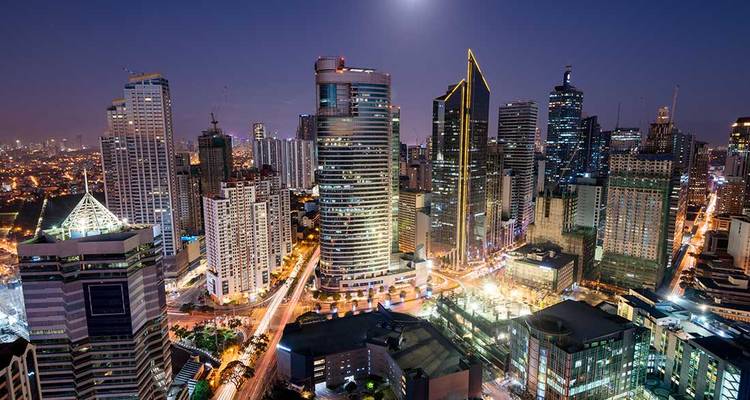 Manila city skyline at night with brightly lit buildings.