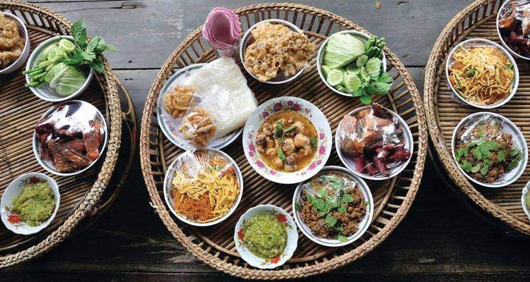 Collations et salades thaïlandaises dans des paniers sur une table en bois.