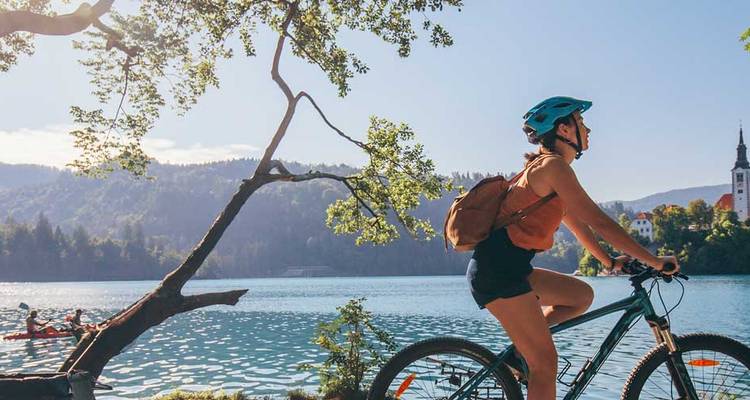 Femme faisant du vélo le long d'un sentier au bord du lac.