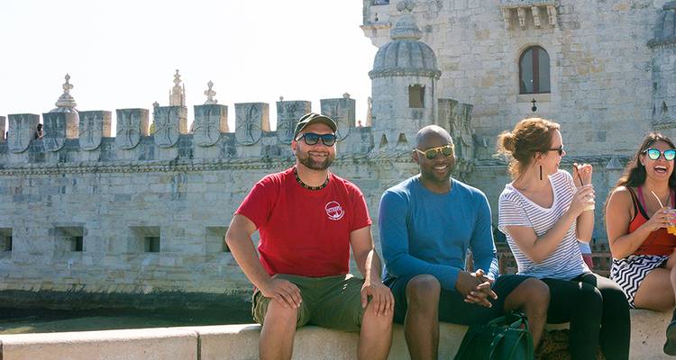 Group of people seated in front of a historic building.