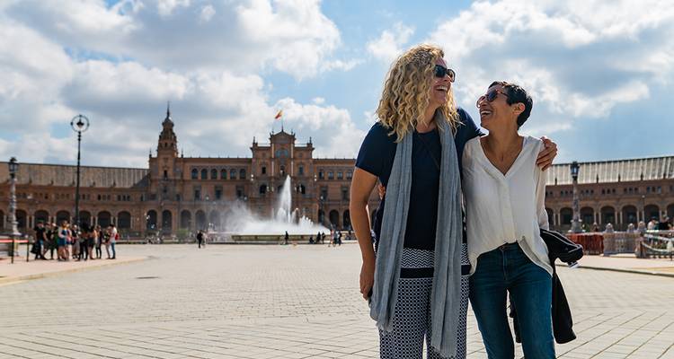 Deux femmes marchant sur une place avec une fontaine.