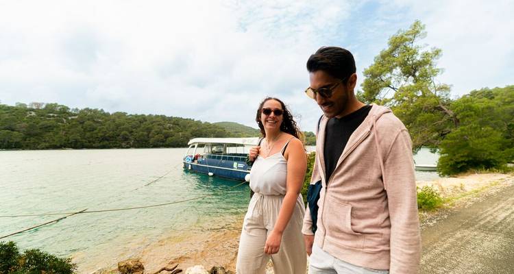 Couple walking beside docked boat.