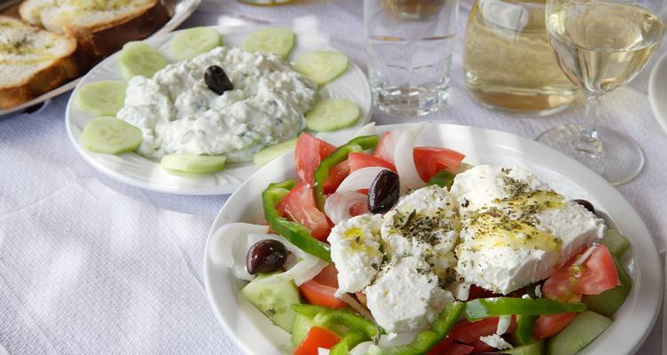 Assorted Greek dishes including salad and tzatziki on a table.