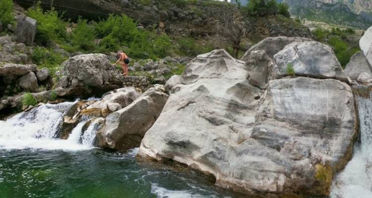 Personne explorant un terrain rocheux avec un ruisseau.