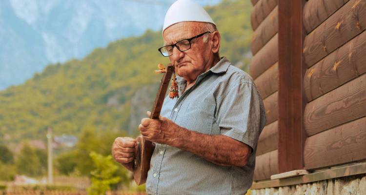 Homme jouant un instrument à cordes traditionnel en plein air.