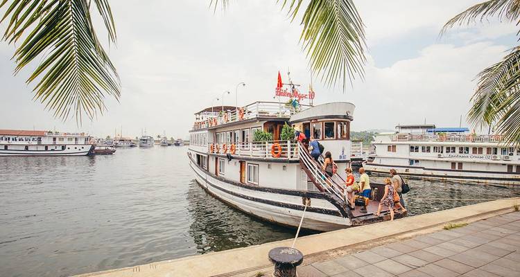 Personas abordando un barco, con palmeras enmarcando la escena.
