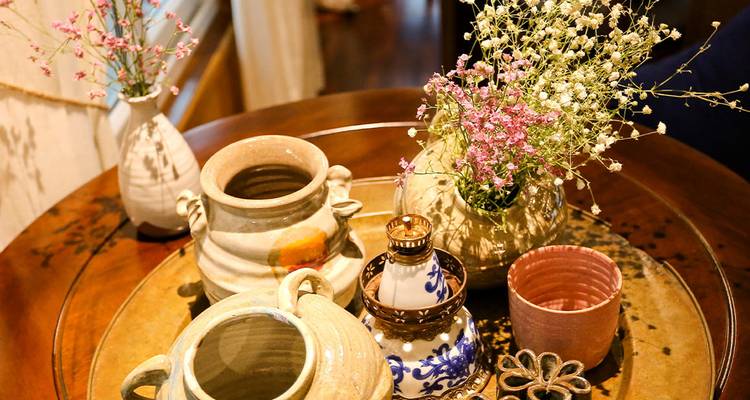 Colección de jarrones de cerámica con flores sobre una mesa de madera.
