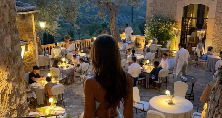 Espace de restauration extérieur avec des personnes assises à des tables, profitant d'une vue sur le jardin.
