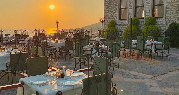 Espace de restauration en plein air avec des tables dressées face au soleil couchant.