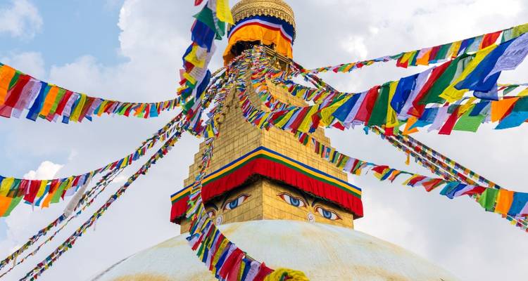 Drapeaux de prière colorés contre un grand stupa avec des yeux de Bouddha.