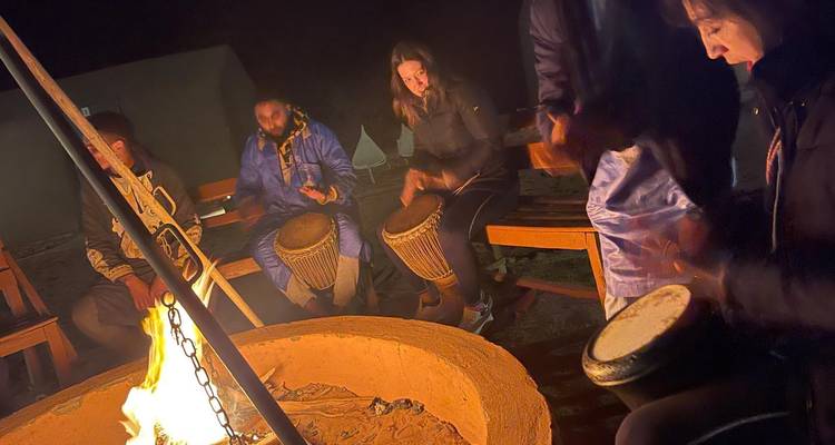 Un groupe de personnes jouant du tambour autour d'un feu de camp la nuit.