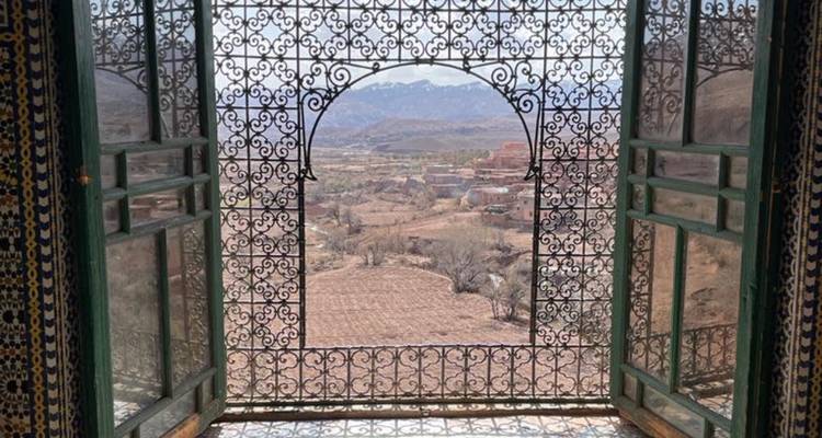 Vue à travers une fenêtre décorative montrant un vaste paysage.