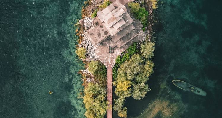 Une vue aérienne d'une petite île avec un bâtiment et un bateau à proximité.