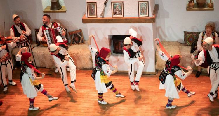 Un groupe de personnes en tenue traditionnelle exécutant une danse à l'intérieur.
