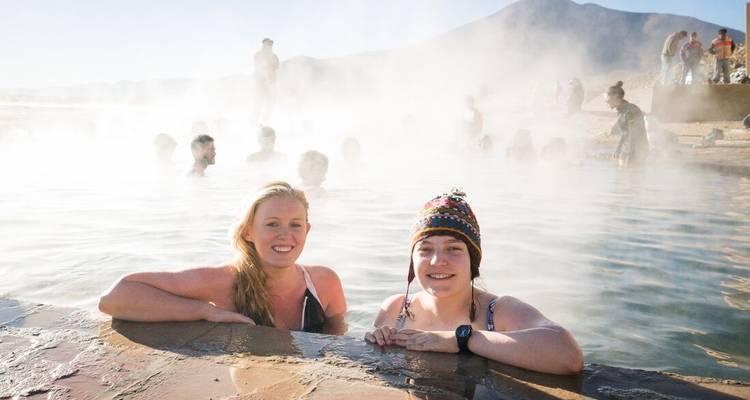 People enjoying a hot spring with steam rising.