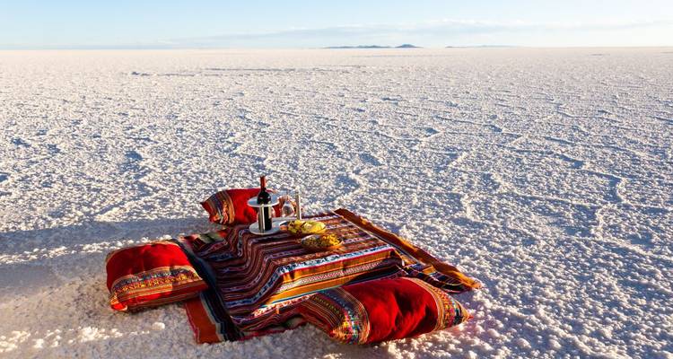 A picnic setup in the vast salt flats under a blue sky.