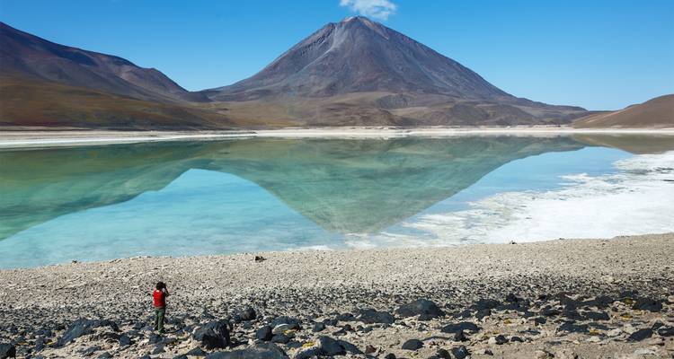 Een grote berg die symmetrisch weerkaatst in een kalm meer.